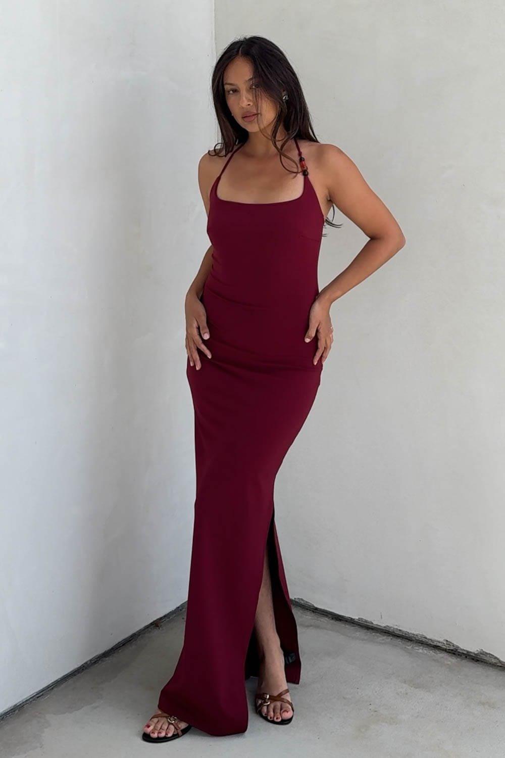 An Elegant And Sophisticated Scoop Halter Neck Bodycon Maxi Dress That Beautifully Combines A Clean, Minimalist Silhouette With Striking Modern Updates. The Dress Is Designed With A Contemporary Scoop Neckline And A Delicate Halter Strap Accent Adorned With Unique Beaded Hardware. Style This Gorgeous Burgundy Dress With Strappy Heeled Sandals And Minimal Accessories For A Polished Cocktail Event, A Romantic Dinner Date, Or An Upscale Evening Wedding Guest Ensemble. – Sophisticated Column Maxi Dress Silhouette Featuring A Figure-Sculpting Bodycon Fit – Flattering Ankle-To-Floor Length Hemline Equipped With A Subtle Side Slit For Elegant Mobility – Versatile Glamorous Design Perfect For Evening Cocktail Parties, Formal Dates, Or Special Occasions Fabric Content: (S7964D) image